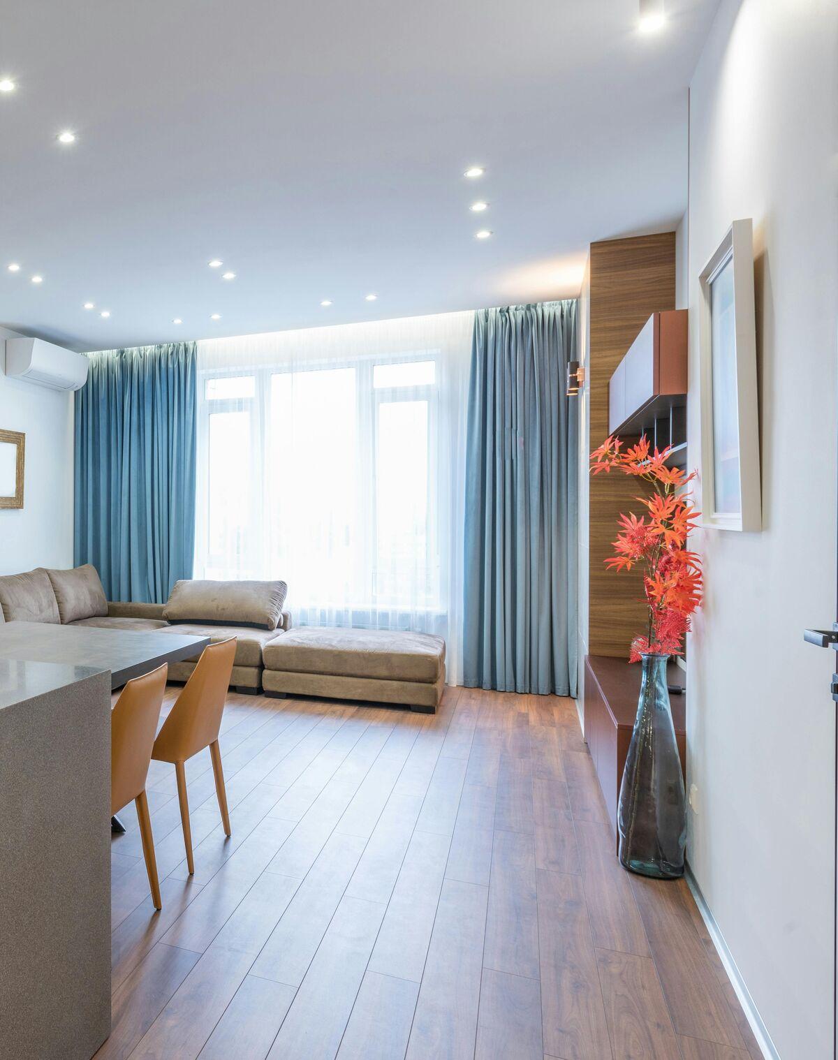 Open-plan living room with full-length blue curtains and sheers