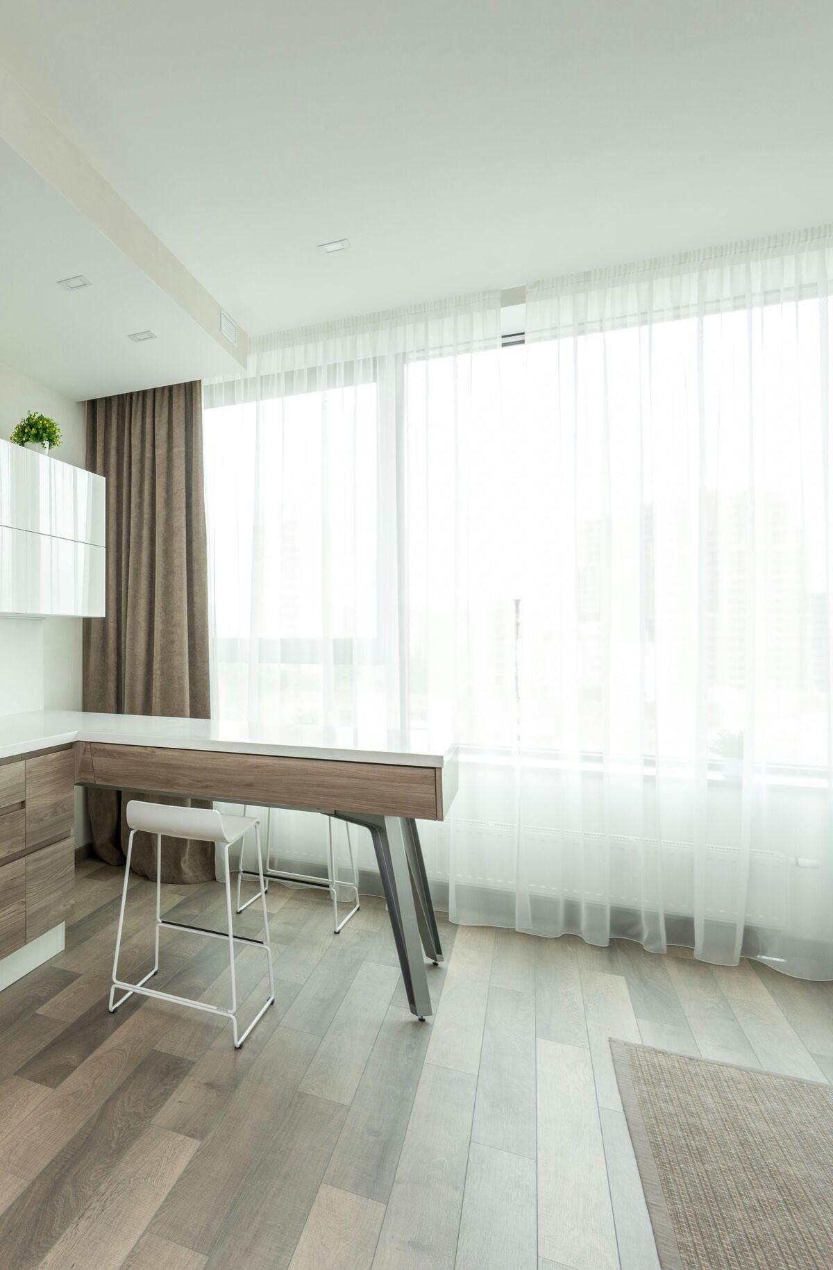 Floor-to-ceiling white sheer curtains on a ceiling track beside a tall window